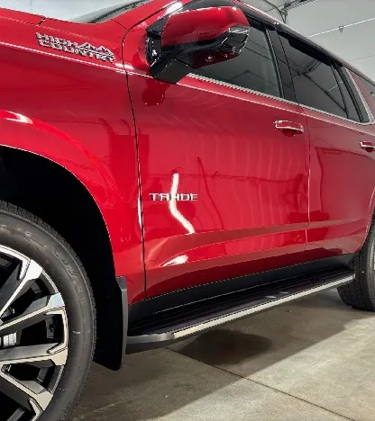 Red GMC Yukon Denali exterior after detailing, side view showing running boards and wheels