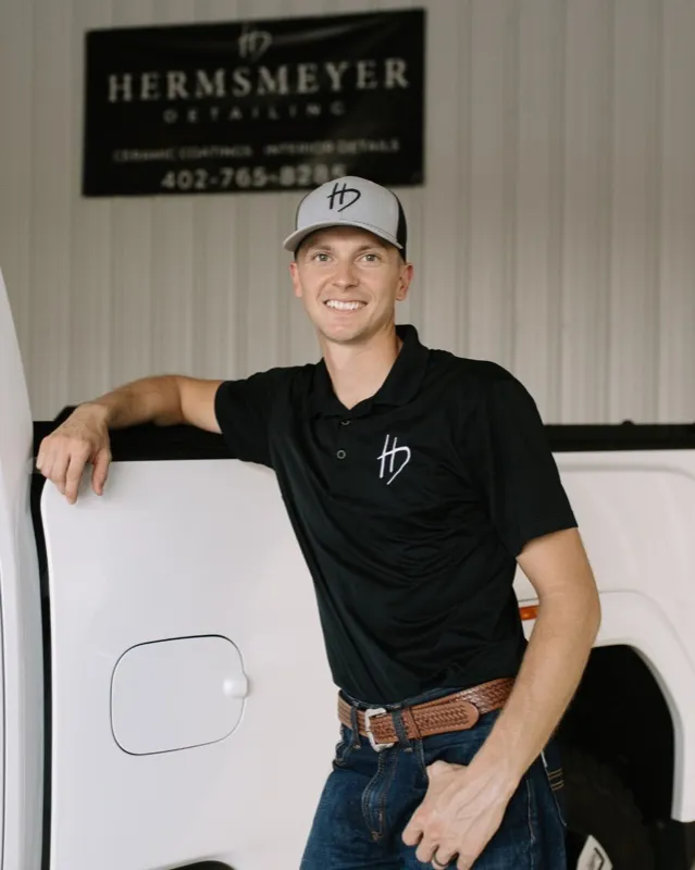 Rusty Hermsmeyer, co-owner of Hermsmeyer Detailing, smiling in front of a white truck